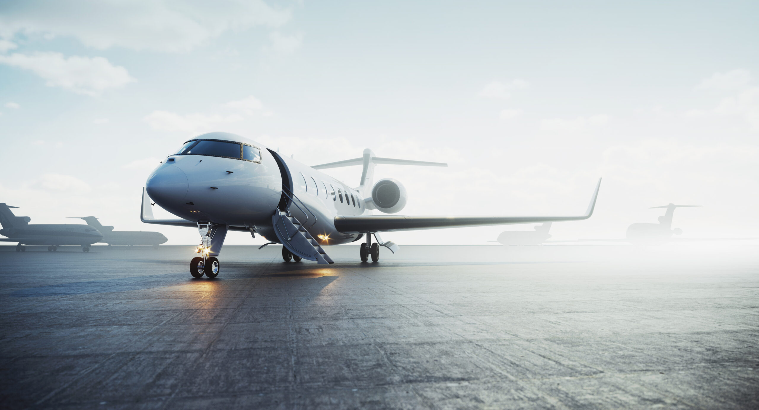 Private jet on runway under a clear sky, ready for departure, with other aircrafts in the background.
