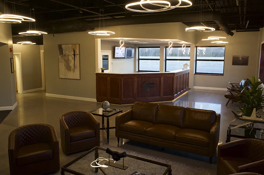 Modern office lobby with stylish lighting, brown leather furniture, and a wooden reception desk.